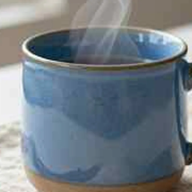 Close-up of a blue ceramic mug from a heavily compressed small JPEG, with smeared glaze and blocky steam