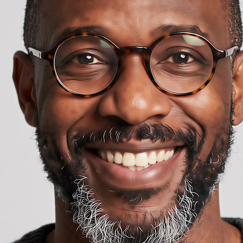 The same face after Enhance + upscale at 4096 pixels, with clear eyes, crisp tortoiseshell glasses and a detailed gray beard